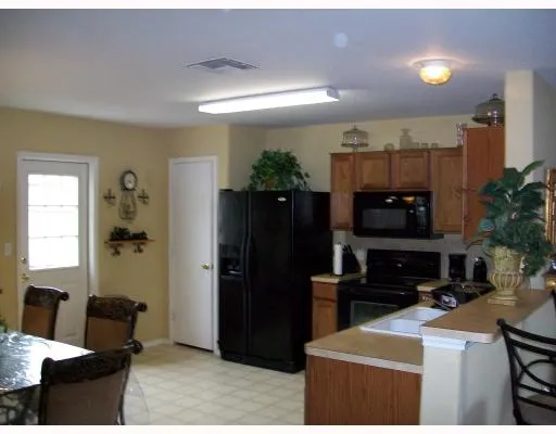 a kitchen with stainless steel appliances kitchen island granite countertop a refrigerator a stove a sink and a dining table with wooden floor