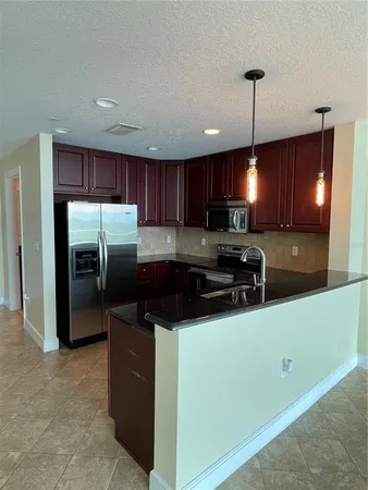 a kitchen with stainless steel appliances granite countertop a refrigerator a sink a stove and a wooden cabinets