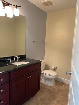 a bathroom with a granite countertop sink and a toilet
