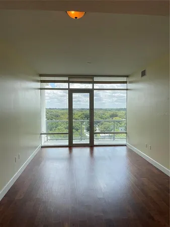 a view of an empty room with wooden floor and a window
