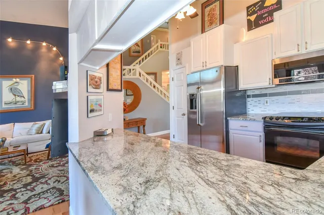 a kitchen with stainless steel appliances granite countertop a sink and a refrigerator