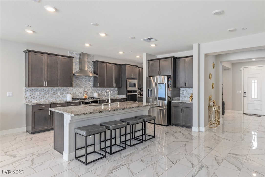 5592 Hickory Tree Street Las Vegas, NV 89149 - Photo 28 of 87 Kitchen with a breakfast bar, stainless steel appliances, light stone countertops, light marble finish flooring, and recessed lighting