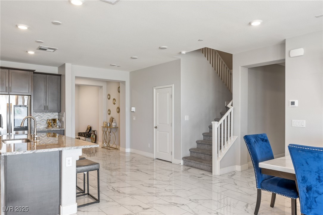 5592 Hickory Tree Street Las Vegas, NV 89149 - Photo 30 of 87 Kitchen featuring light stone countertops, smart refrigerator, light marble finish flooring, recessed lighting, and a breakfast bar area