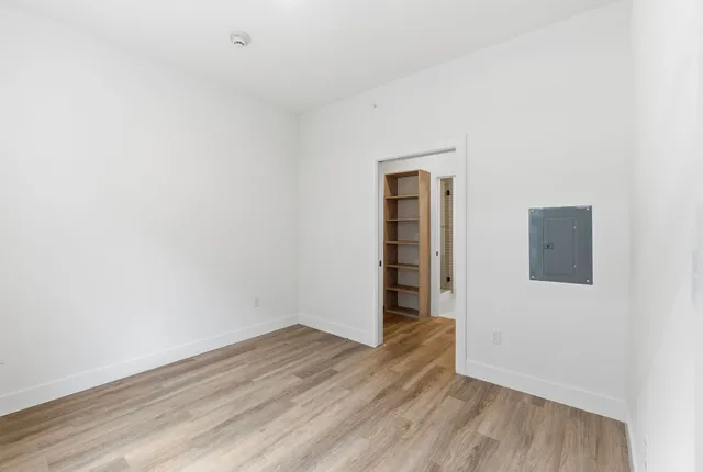 an empty room with wooden floor and windows