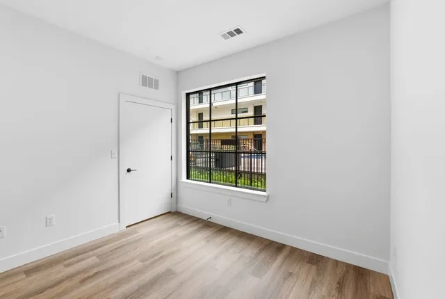 an empty room with wooden floor and windows