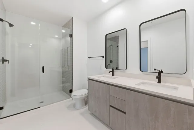 a bathroom with a double vanity sink toilet and shower
