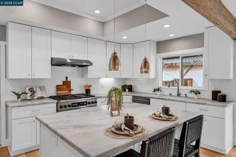 a kitchen with stainless steel appliances granite countertop a sink white cabinets and a stove