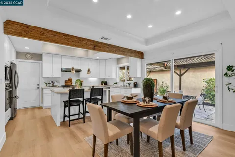 a kitchen with stainless steel appliances kitchen island granite countertop a dining table chairs and a microwave
