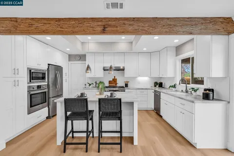 a kitchen with a center island white cabinets and stainless steel appliances