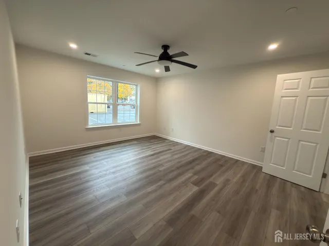 an empty room with wooden floor ceiling fan and windows