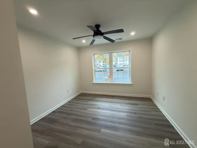 an empty room with wooden floor ceiling fan and windows