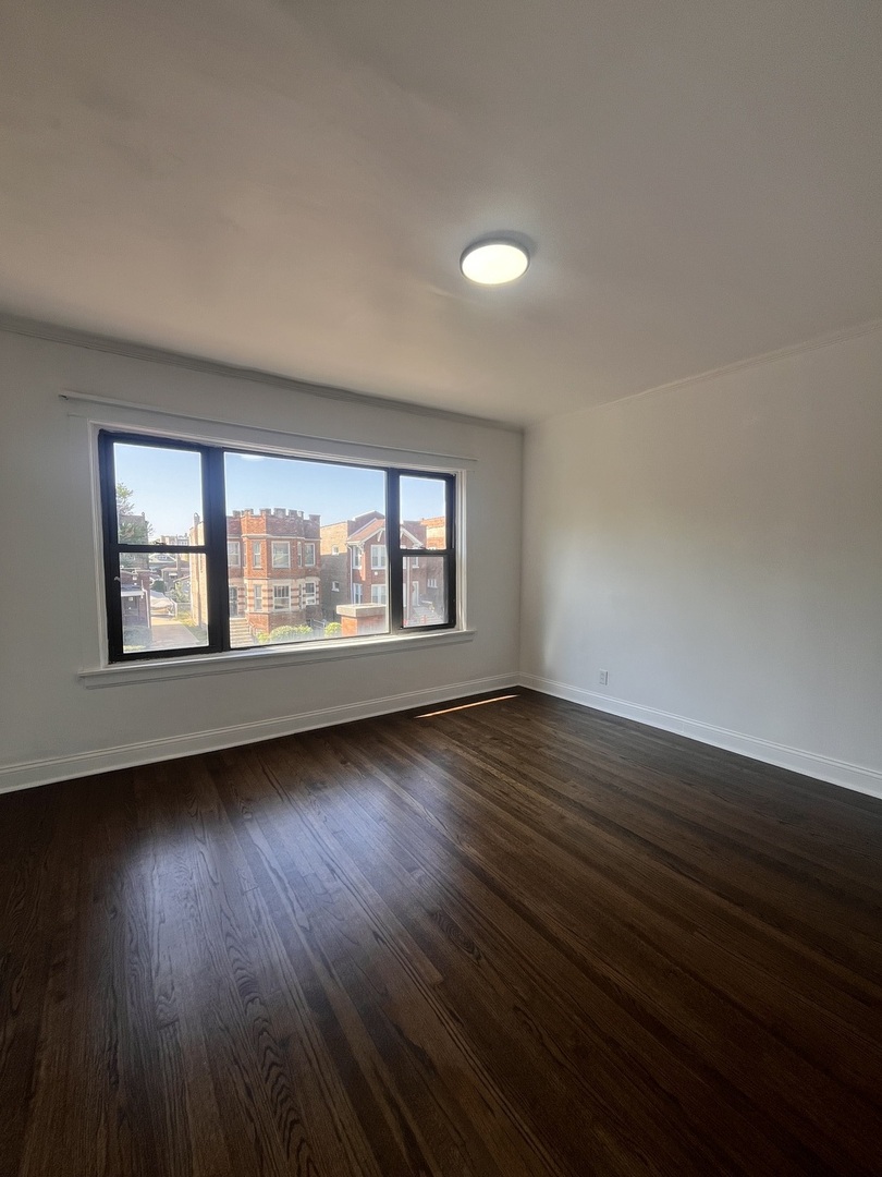 7955 South Elizabeth Street, Unit 2 Chicago, IL 60620 - Photo 5 of 10 a view of an empty room with wooden floor and a window
