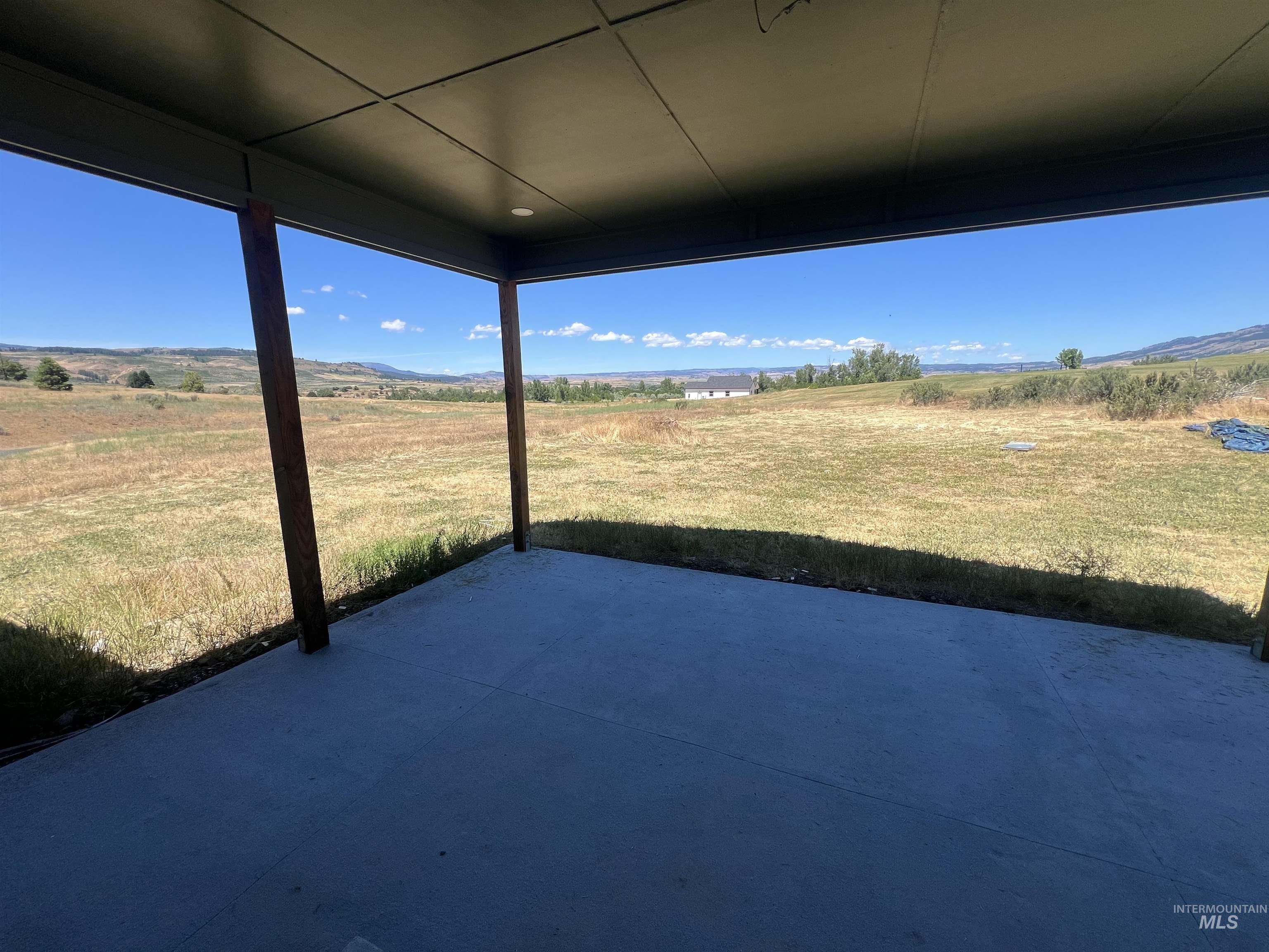 2300 Golf Council, ID 83612 - Photo 6 of 17 Covered patio with a concrete surface, supported by dark posts, opening onto an expansive natural landscape with distant hills under a clear sky