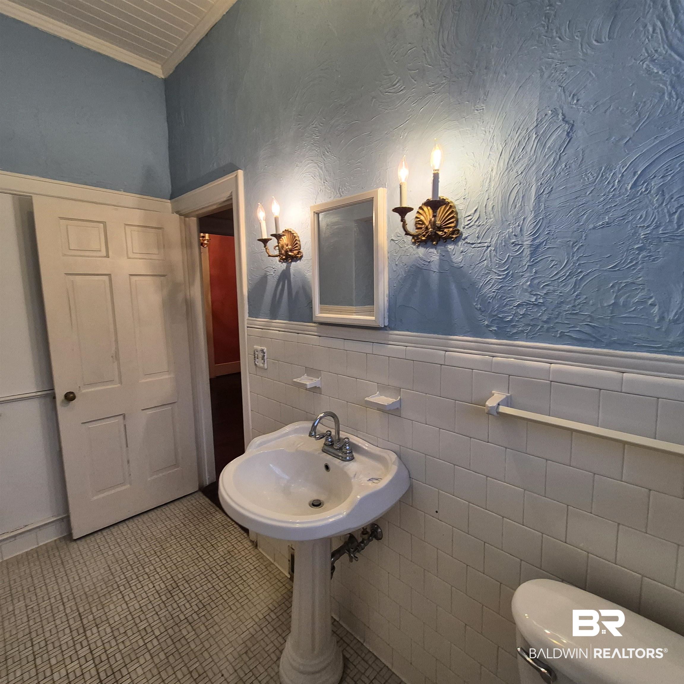 308 Rural Street Evergreen, AL 36401 - Photo 14 of 40 Half bath with a wainscoted wall, tile walls, ornamental molding, a textured wall, and tile patterned flooring