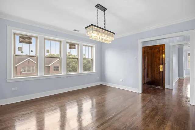 a view of an empty room with wooden floor cabinets and a chandelier