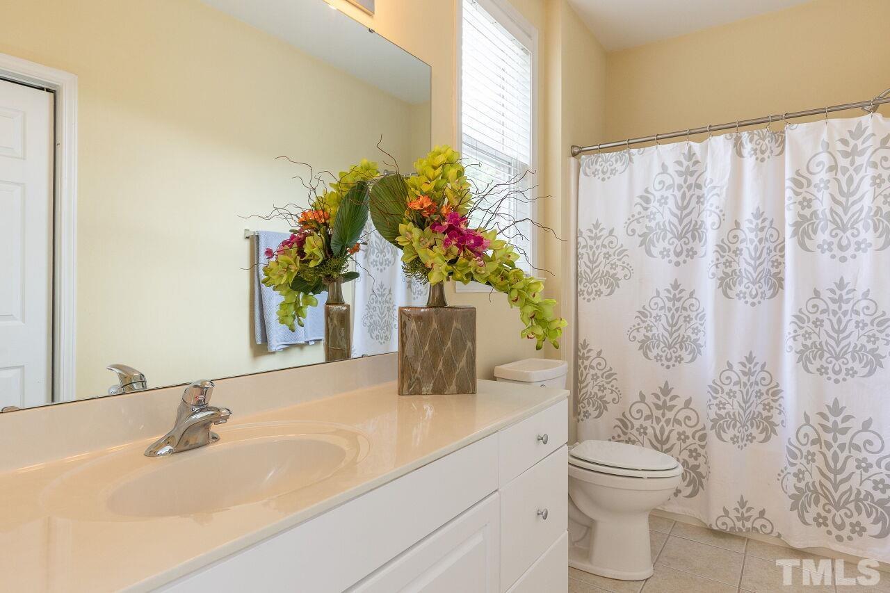 208 West Savannah Ridge Road, Unit 208 Holly Springs, NC 27540 - Photo 14 of 30 a bathroom with a granite countertop sink a toilet and a mirror