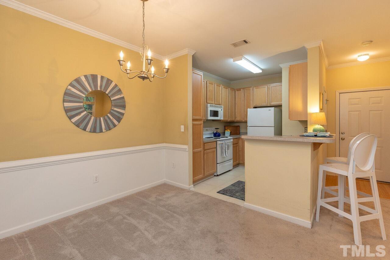 208 West Savannah Ridge Road, Unit 208 Holly Springs, NC 27540 - Photo 10 of 30 a kitchen with stainless steel appliances kitchen island granite countertop a refrigerator a stove top oven a sink with island and chairs