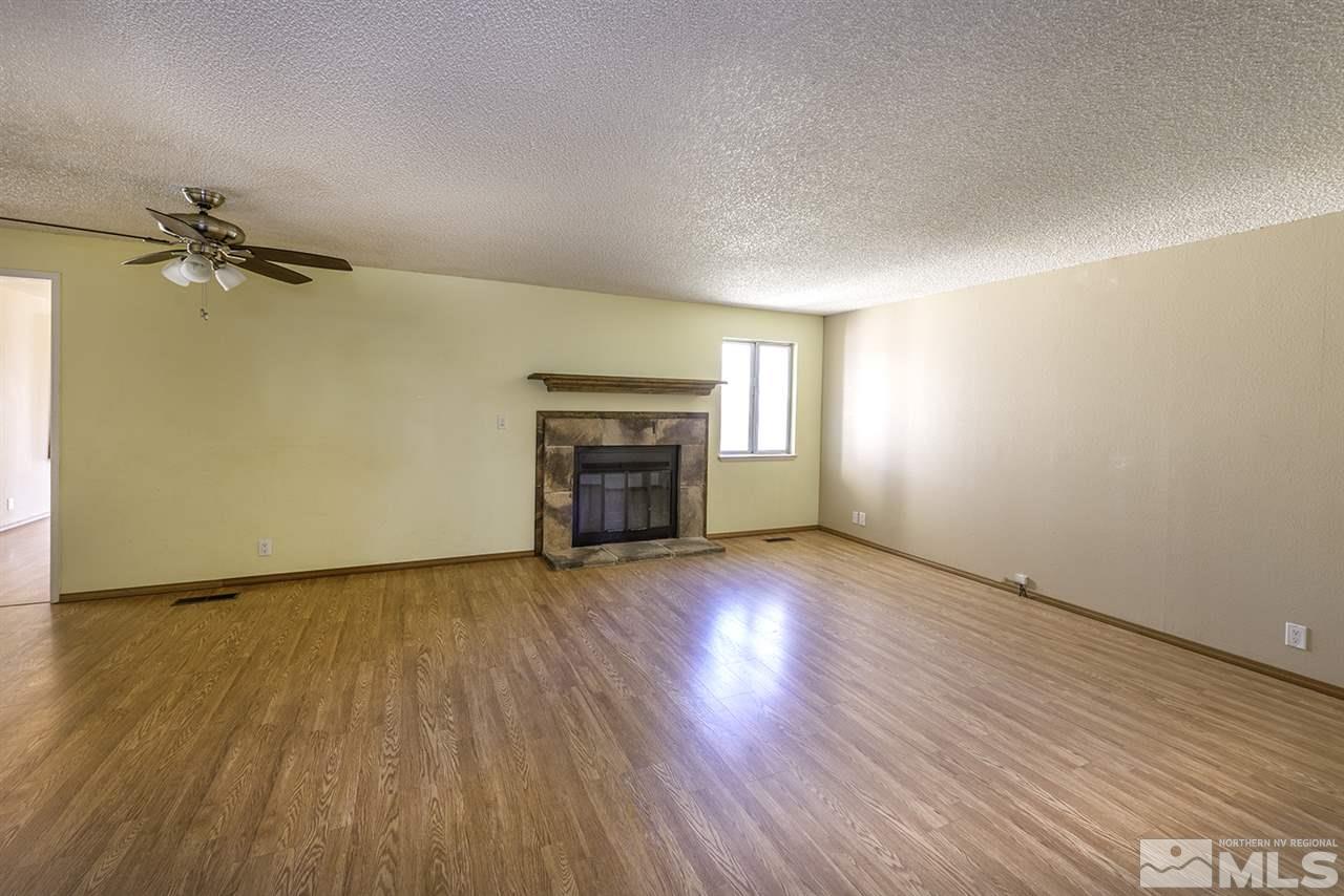 165 Ring Road Dayton, NV 89403 - Photo 3 of 19 an empty room with wooden floor fireplace and windows