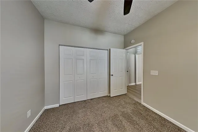 an empty room with a chandelier fan and windows