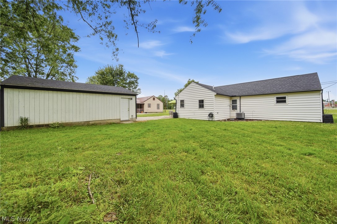 3471 State Rte 5 Newton Falls, OH 44444 - Photo 24 of 31 Expansive green lawn with a detached storage building featuring white siding and a dark shingle roof