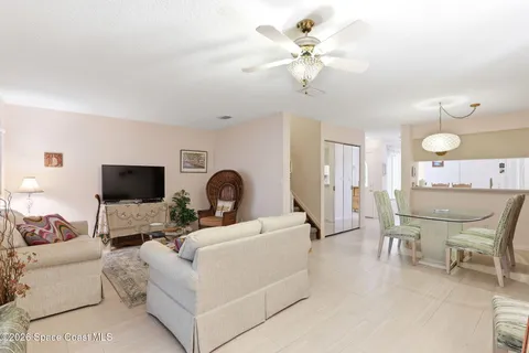a living room with furniture a flat screen tv and a ceiling fan