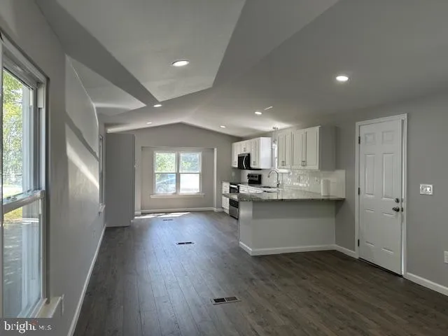 a kitchen with granite countertop a stove a sink and a refrigerator