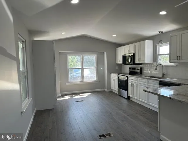 a kitchen with granite countertop white cabinets and stainless steel appliances