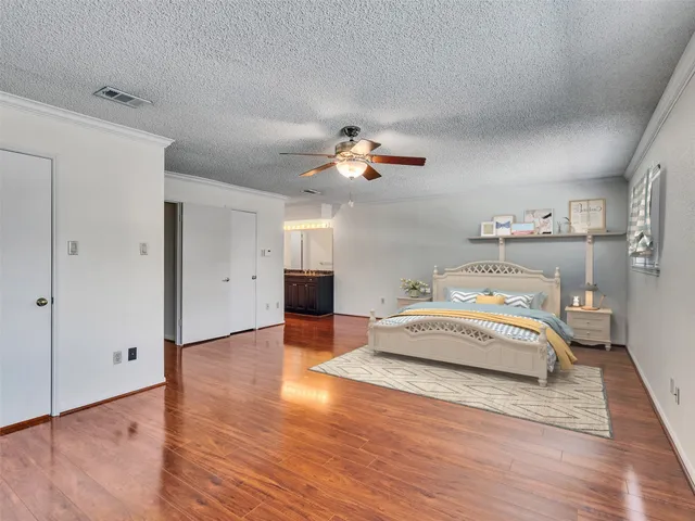 a spacious bedroom with a bed and wooden floor
