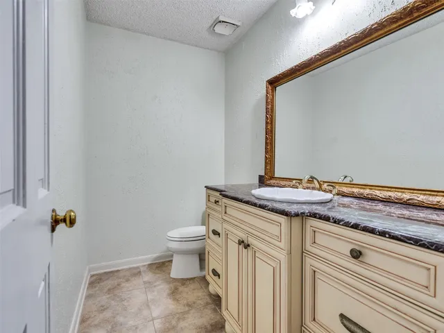a bathroom with a granite countertop toilet and a sink