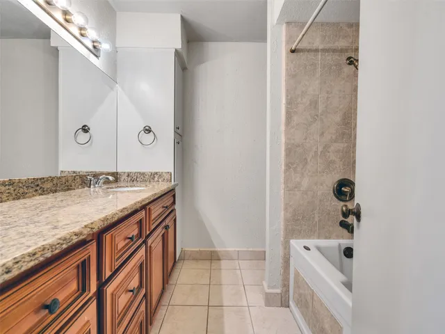 a bathroom with a granite countertop sink a mirror and a bathtub