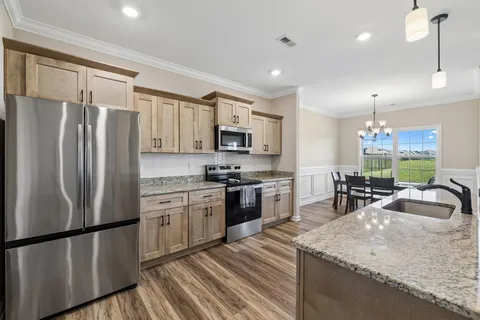 a kitchen with stainless steel appliances granite countertop a refrigerator a sink dishwasher a oven with white cabinets and wooden floor