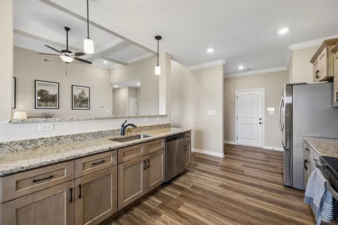 a large kitchen with granite countertop a large kitchen island white cabinetry and stainless steel appliances