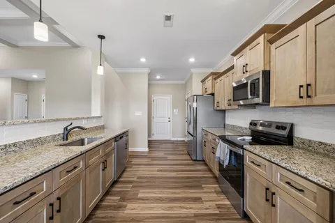 a large kitchen with stainless steel appliances granite countertop a lot of counter space and wooden floor