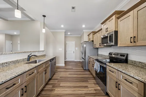 a large kitchen with stainless steel appliances granite countertop a lot of counter space and wooden floor