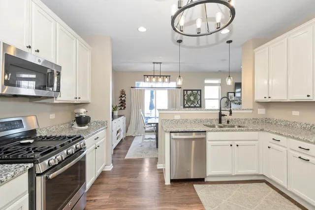 a kitchen with stainless steel appliances granite countertop a stove a sink dishwasher and a microwave oven with large wooden cabinets