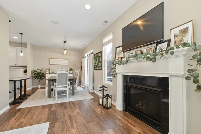 a living room with stainless steel appliances furniture a fireplace a flat screen tv and kitchen view