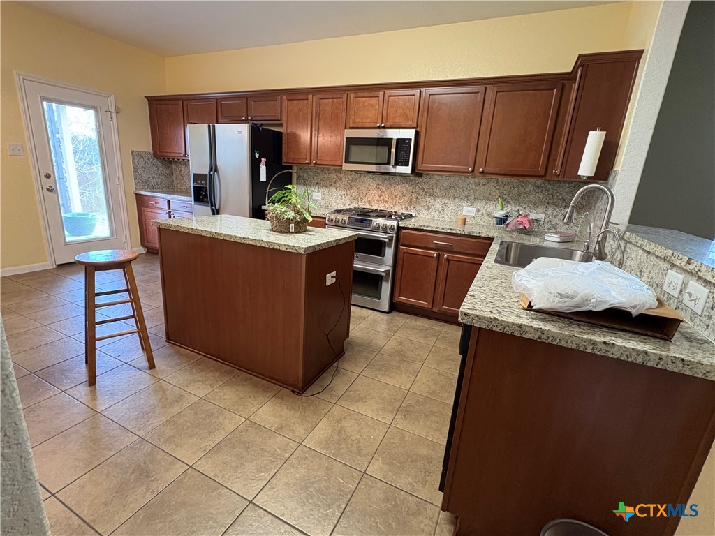 102 Wisteria Way San Marcos, TX 78666 - Photo 10 of 30 a kitchen with kitchen island granite countertop a sink stove and cabinets