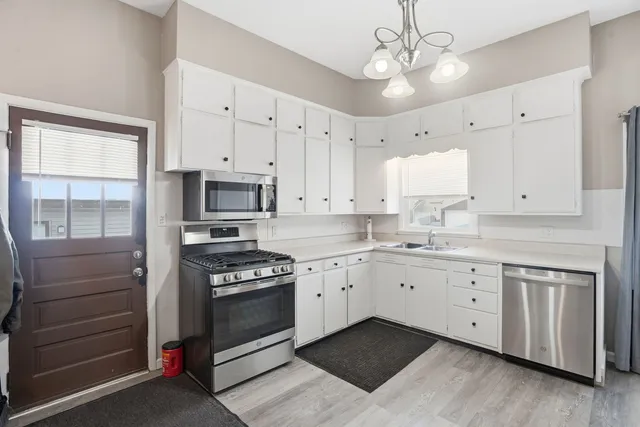 a kitchen with granite countertop white cabinets and stainless steel appliances