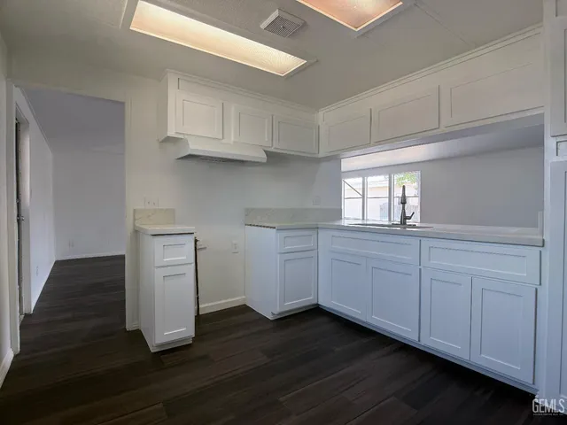 a kitchen with wooden floors and white cabinets