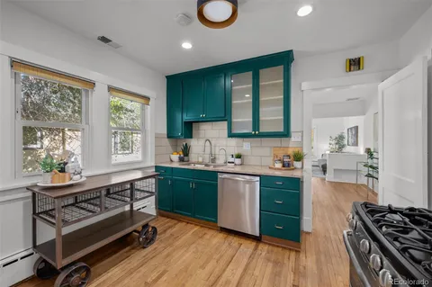 a kitchen with stainless steel appliances granite countertop a stove a sink dishwasher and cabinets with wooden floor