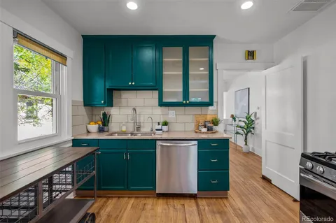 a kitchen with a sink cabinets window and wooden floor