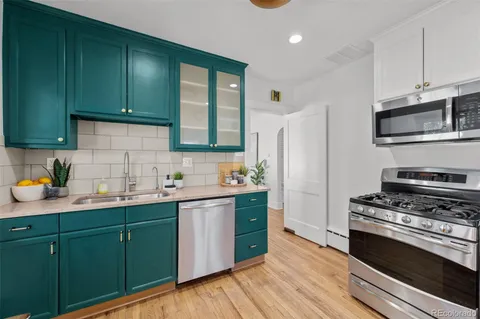 a kitchen with stainless steel appliances a stove cabinets and wooden floor