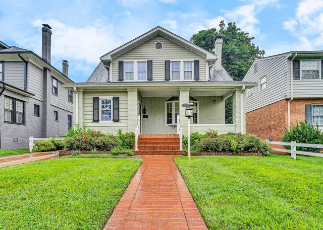 a front view of a house with a yard and potted plants