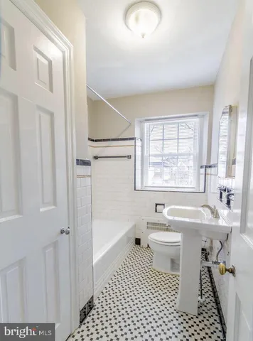 a bathroom with a sink a toilet a window and shower