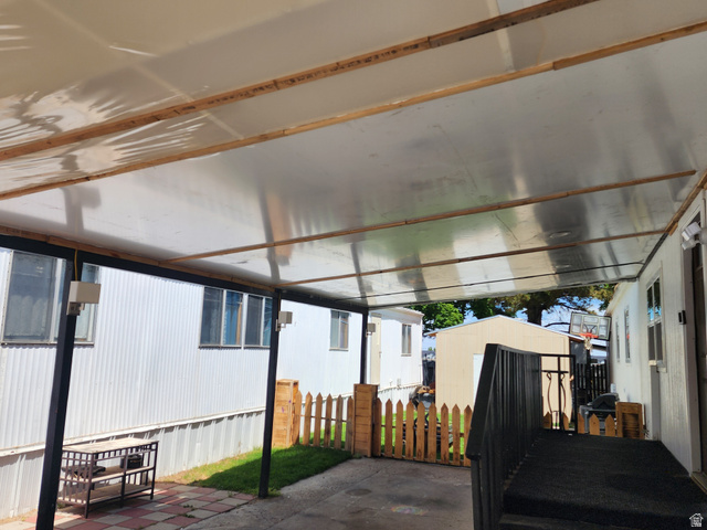 332 Joshua Street Tooele, UT 84074 - Photo 16 of 16 Covered patio area featuring a translucent roof panel, exposed wood beam supports, and black metal support posts