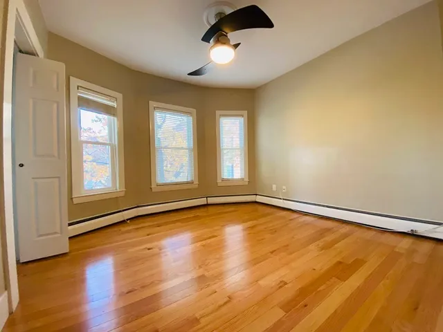 a view of an empty room with window and wooden floor