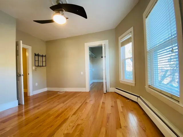a view of an empty room with a window and wooden floor