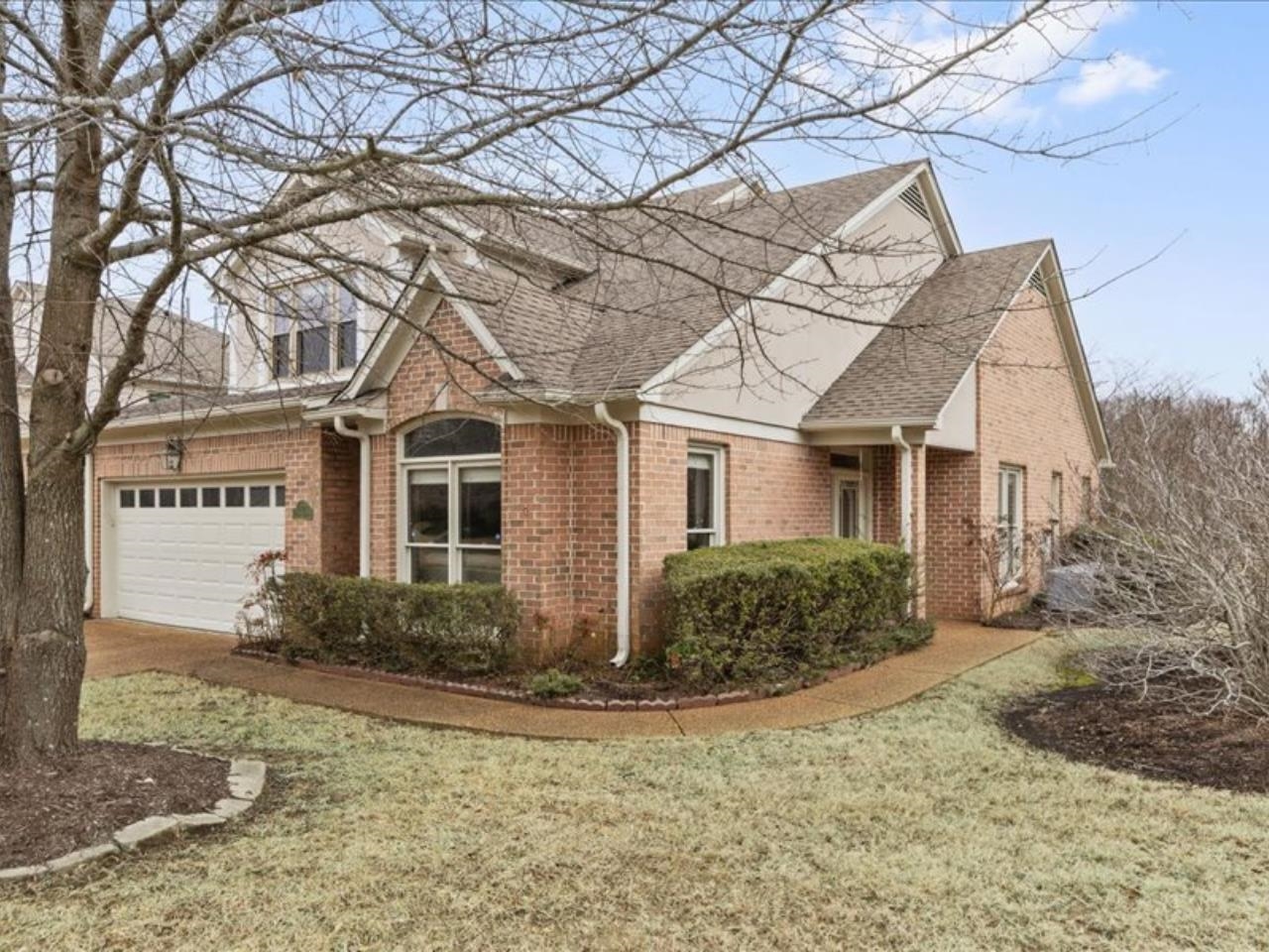 1672 Village Ridge Road, Unit 69 Collierville, TN 38017 - Photo 3 of 23 View of property exterior featuring roof with shingles, brick siding, a garage, and a yard