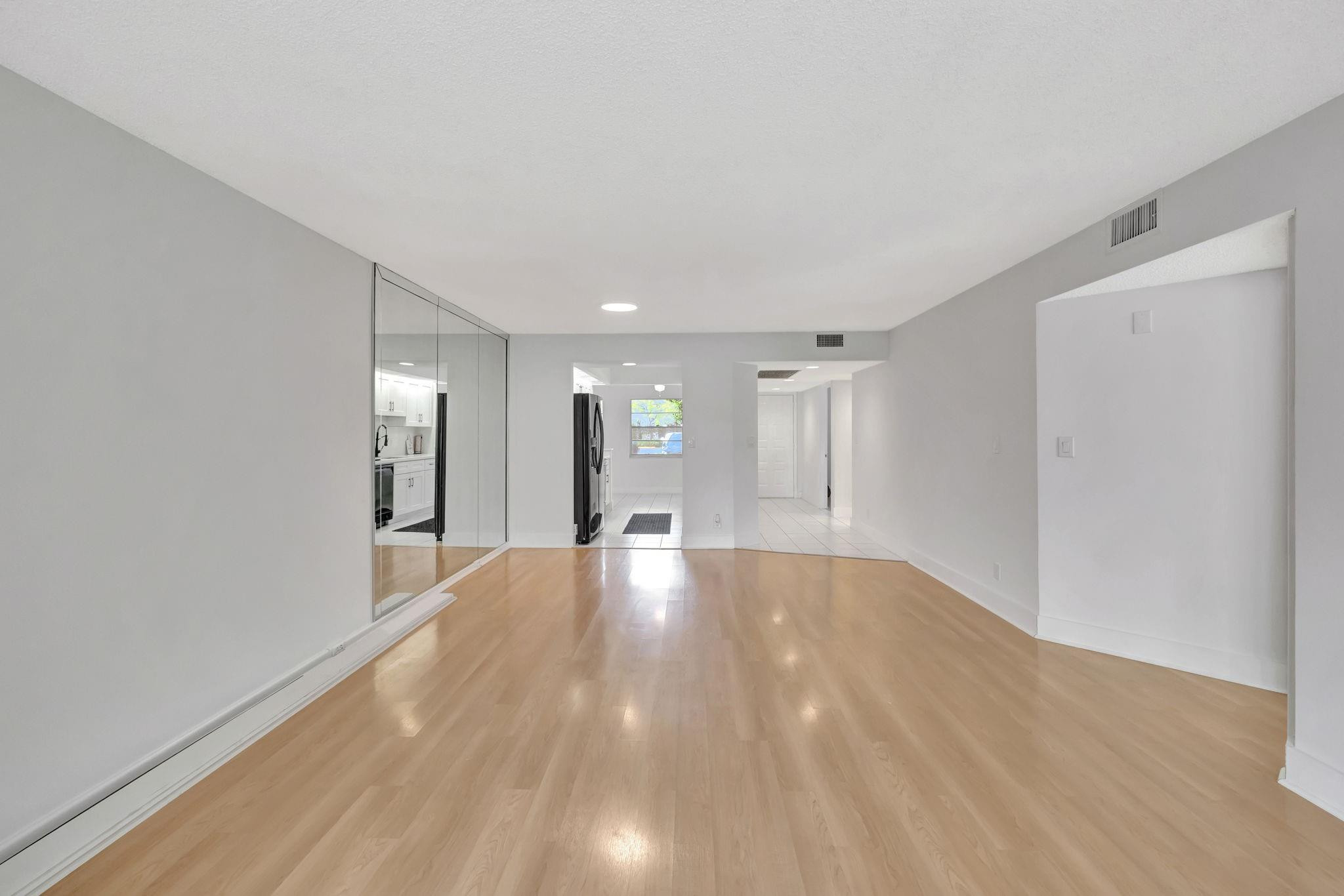 1801 Eleuthera Point, Unit E1 Coconut Creek, FL 33066 - Photo 15 of 50 a view of an empty room with wooden floor and a window