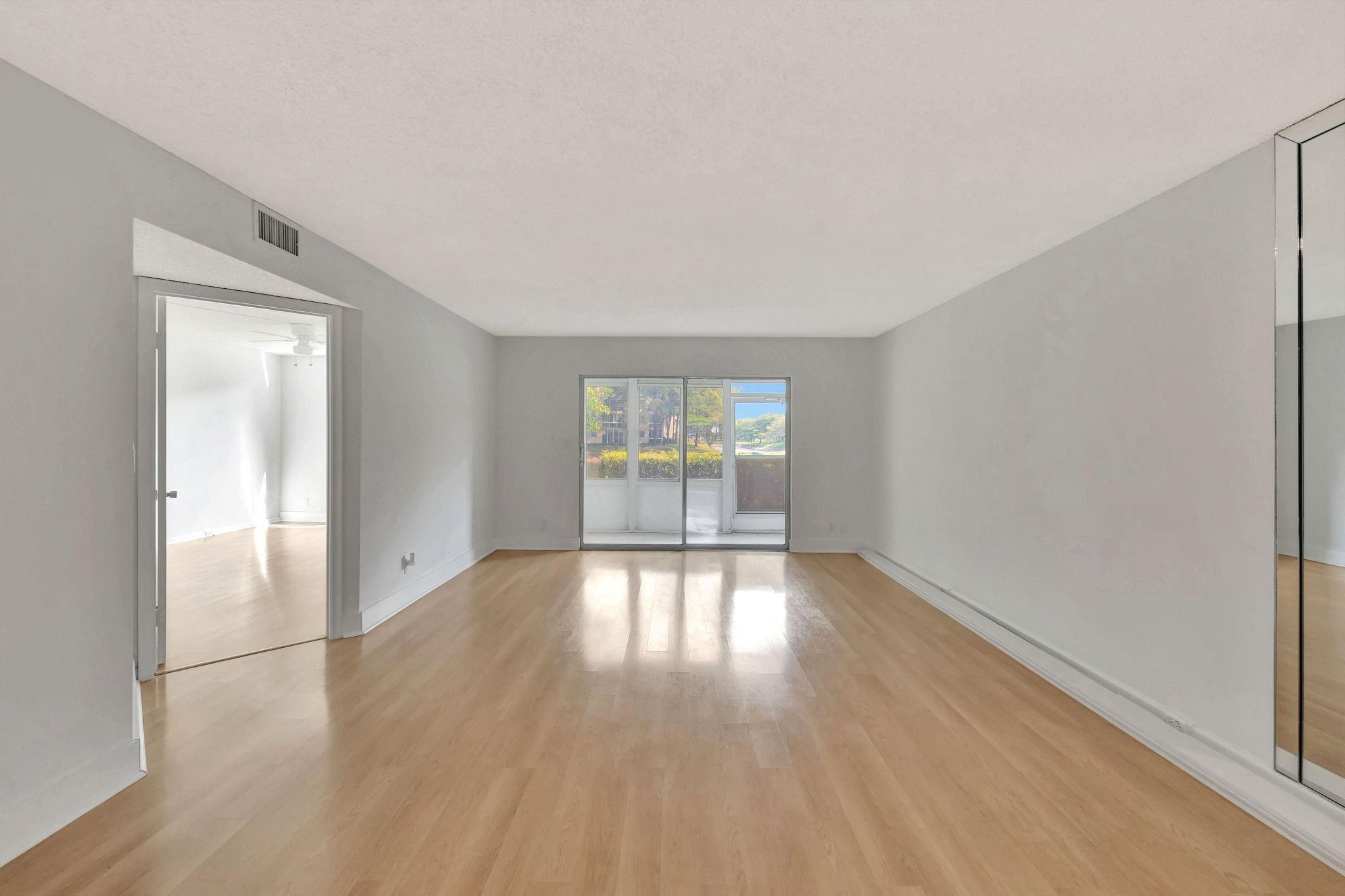 1801 Eleuthera Point, Unit E1 Coconut Creek, FL 33066 - Photo 16 of 50 an empty room with wooden floor and windows